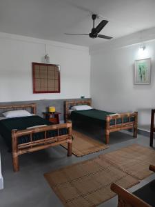 a room with three beds and a ceiling fan at Longchen Homestay in Dimapur