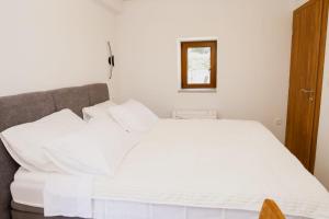 a white bed with white pillows in a bedroom at Aurora in Ljubuški