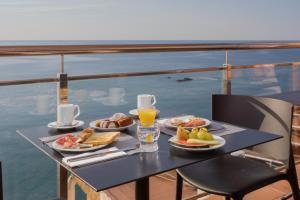 ein Tisch mit Tellern voller Speisen und Getränken auf einem Balkon in der Unterkunft Hotel Cap Roig & Spa by Brava Hoteles in Platja  d'Aro