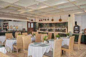 ein Restaurant mit Tischen und Stühlen und einer Küche in der Unterkunft Hotel Cap Roig & Spa by Brava Hoteles in Platja  d'Aro