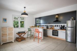 a kitchen with a refrigerator and a table and chairs at DOUC 'IRMA Appt T3 à 5 mn à pied de la Plage de l'anse à L'âne in Les Trois-Îlets +18 photos