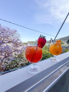 Zwei Cocktails stehen auf einem Sims mit Aussicht in der Unterkunft Volcano Glow in Methana