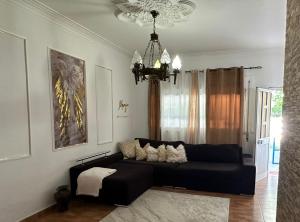 a black couch in a living room with a chandelier at Marujo Home & Heart in Penedo Gordo