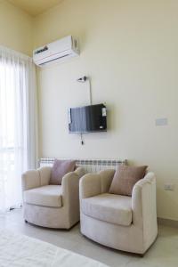a living room with two chairs and a tv on the wall at Saint Paul Guesthouse in Zahlé