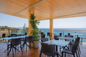 eine Terrasse mit Tischen und Stühlen und Meerblick in der Unterkunft Hotel Cap Roig & Spa by Brava Hoteles in Platja  d'Aro + 35 Fotos