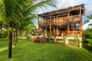 a house with a palm tree in front of it at Reserva Pratigi in Ituberá