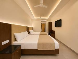 a hotel room with two beds and a television at Arthana Grand Inn in Udumalaippettai