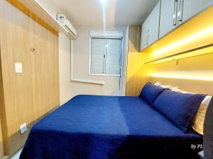 a small bedroom with a blue bed and a window at Graciosa Reserva Ipanema in Porto Alegre