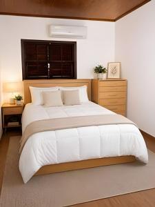a bedroom with a large white bed and a window at Chalé Charmoso na Serra de Penedo in Penedo