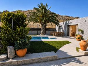 a backyard with a swimming pool and palm trees at ARMONIA 1 & 2 in Myrina