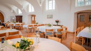 a dining room with white tables and chairs at Bodensee-Schloss Maurach in Uhldingen-Mühlhofen
