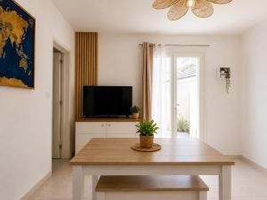 a living room with a table and a tv at La Tropicale - Terrasse Privée Entre Lac & Océan- C' LA VIEconciergerie in Soustons