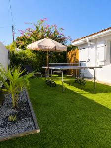 a table and an umbrella in a yard at La Tropicale - Terrasse Privée Entre Lac & Océan- C' LA VIEconciergerie in Soustons