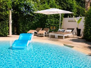 a pool with a blue chair and an umbrella at Villa Lucy Eco Friendly in Fontane Bianche