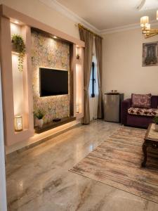 a living room with a couch and a television on a wall at Sol Pyramids Rooftop View Giza in Cairo