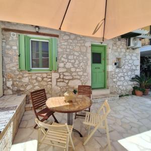 a patio with a table and chairs and an umbrella at Alekos Cozy Stone 2BR Home Karya Center in Lefkada