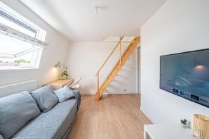 a living room with a couch and a flat screen tv at Maison Cuvier - Spacieuse Maison Idéale Groupes & Pros in Roubaix