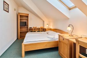 a bedroom with a bed and a desk with a lamp at Hotel Krakonoš in Trutnov