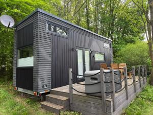 a black tiny house sitting on a wooden deck at Tiny House Hameln in Salzhemmendorf +22 photos