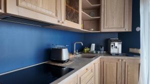 a kitchen with blue walls and wooden cabinets and a sink at Annsmuiža in Salacgrīva