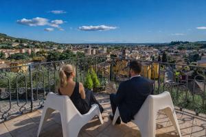 a man and woman sitting on white chairs on a balcony at Panoramic villa near Florence in Pescia