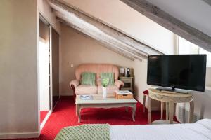a living room with a chair and a tv at Logis Hôtel Auberge Lukaïna in Urrugne