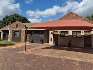 a building with a red roof with a gas station at Fox Inn Guesthouse Lephalale in Lephalale