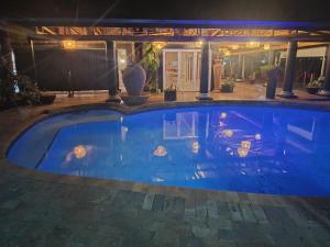 a large swimming pool in a yard at night at Fox Inn Guesthouse Lephalale in Lephalale