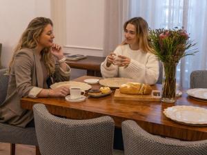 two women sitting at a table with food at Nomad City Suites in Cape Town