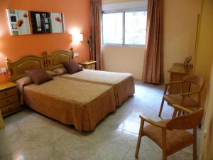 a bedroom with a bed and a chair and a window at Hotel Noguera El Albir in Albir