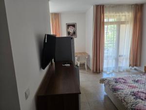 a room with a bed and a dresser with a television at Морски Фар in Sveti Vlas