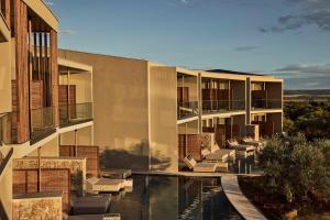 an external view of a building with a swimming pool at Zelia Halkidiki, part of Destination by Hyatt - Adults Only in Nea Potidaea