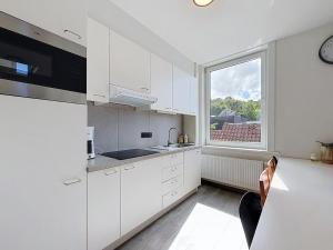 a kitchen with white cabinets and a large window at Stellaross - Koksijde in Koksijde +13 photos