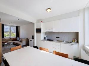 a kitchen and living room with white cabinets and a table at Stellaross - Koksijde in Koksijde