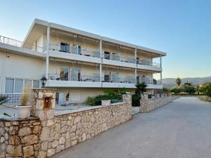 a large white building with a stone wall at Zoom Beach Hotel in Kandia
