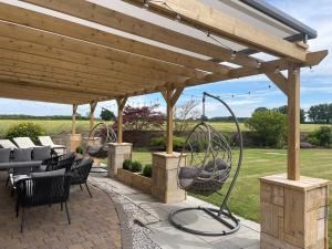 a wooden pergola with chairs and a swing at Deighton Lodge in York +41 photos