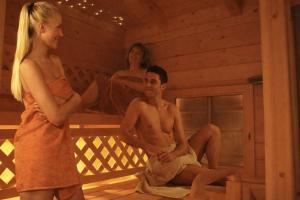 two women standing and a man sitting in a sauna at Fewo TG in Schliersee +9 photos