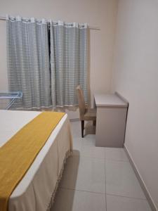 a bedroom with a bed and a desk and a chair at Apartamento Aconchegante 3 in Doutor Lund