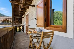 a table and chairs on a balcony with a window at Hostdomus - Inside Alps Suite in Cesana Torinese