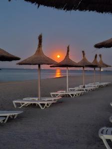a row of beach chairs with umbrellas on a beach at KYA Luxury in Mamaia