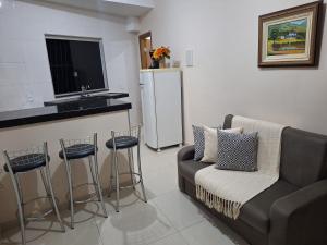 a living room with a couch and a kitchen with a refrigerator at Apartamento Aconchegante 3 in Doutor Lund