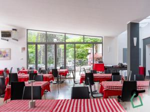 a restaurant with red and white tables and chairs at Hotiday Lago di Levico in Levico Terme