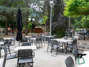 an outdoor patio with tables and chairs and an umbrella at Hotiday Lago di Levico in Levico Terme