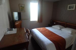 a hotel room with a bed and a table and a television at Cit'Hotel Avallon Vauban in Avallon