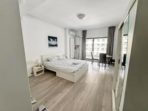 a white bedroom with a bed and a desk at Black Sea Booking - Helsinki in Năvodari
