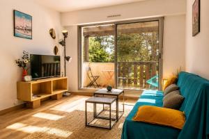 a living room with a blue couch and a tv at Pool 3 Balconies & Parking in La Baule