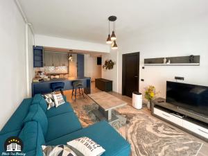 a living room with a blue couch and a kitchen at Black Sea Booking - Helsinki in Năvodari