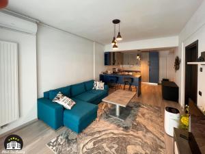 a living room with a blue couch and a kitchen at Black Sea Booking - Helsinki in Năvodari