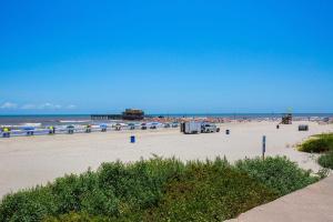 a beach with people and the ocean and a pier at Hyatt Select Galveston Beachfront in Galveston
