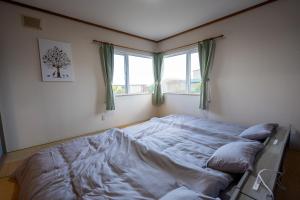 a bed in a bedroom with two windows at Seaside Deer Shiraoi in Shiraoi